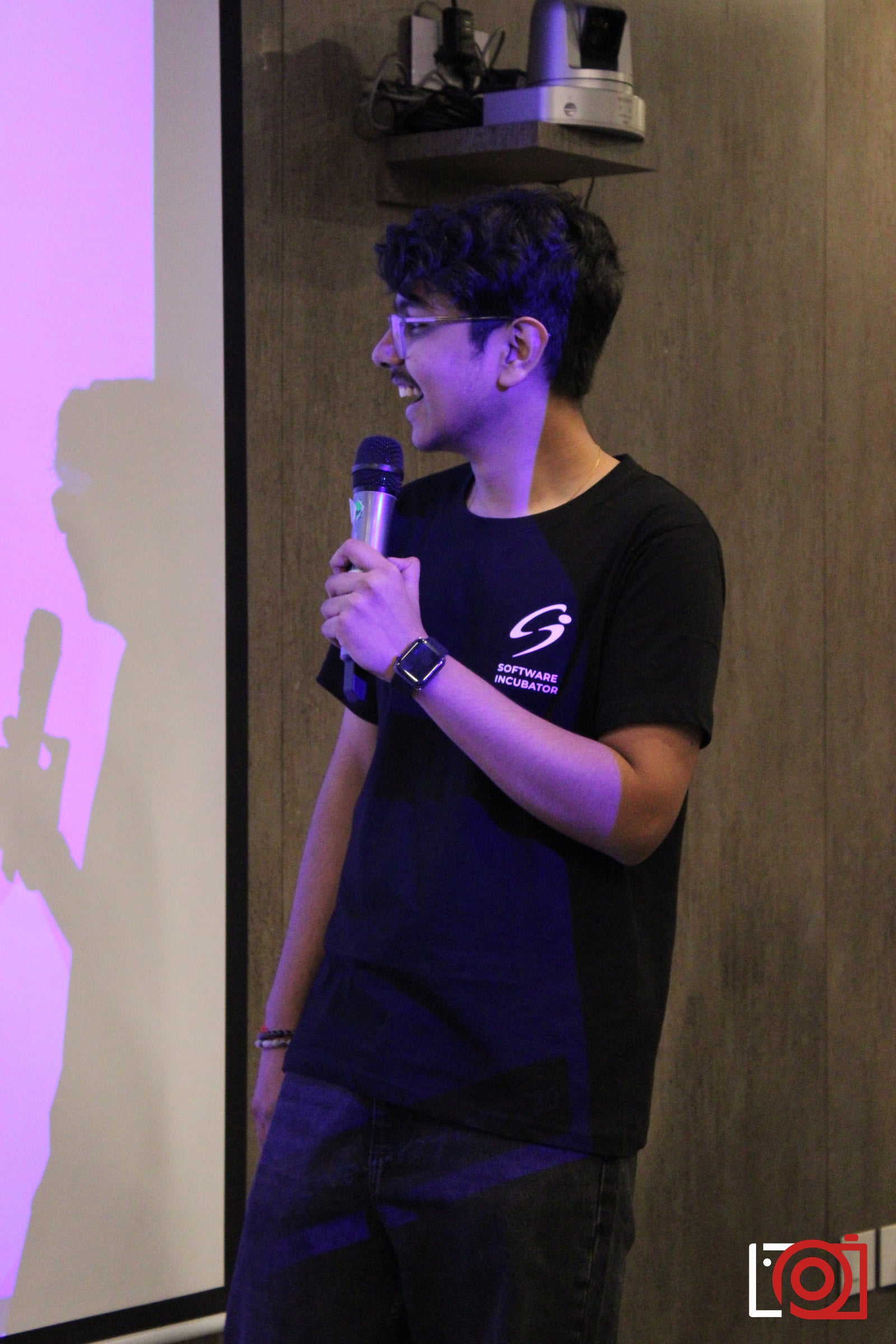 Archas on stage with a microphone, hosting the Runtym workshop.